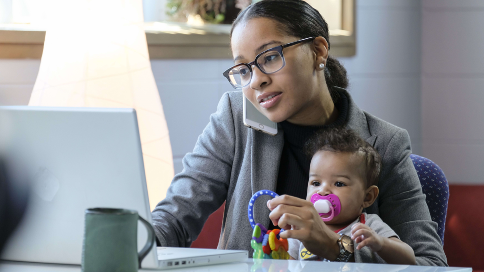 woman holding baby and working on computer