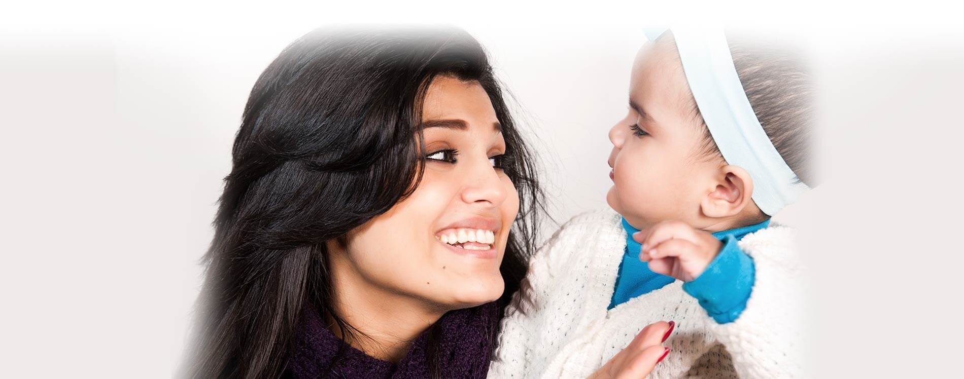 A mother smiling while holding her child.