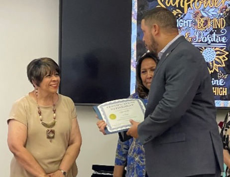 A gentleman is presenting a certificate to Pam Hunt.