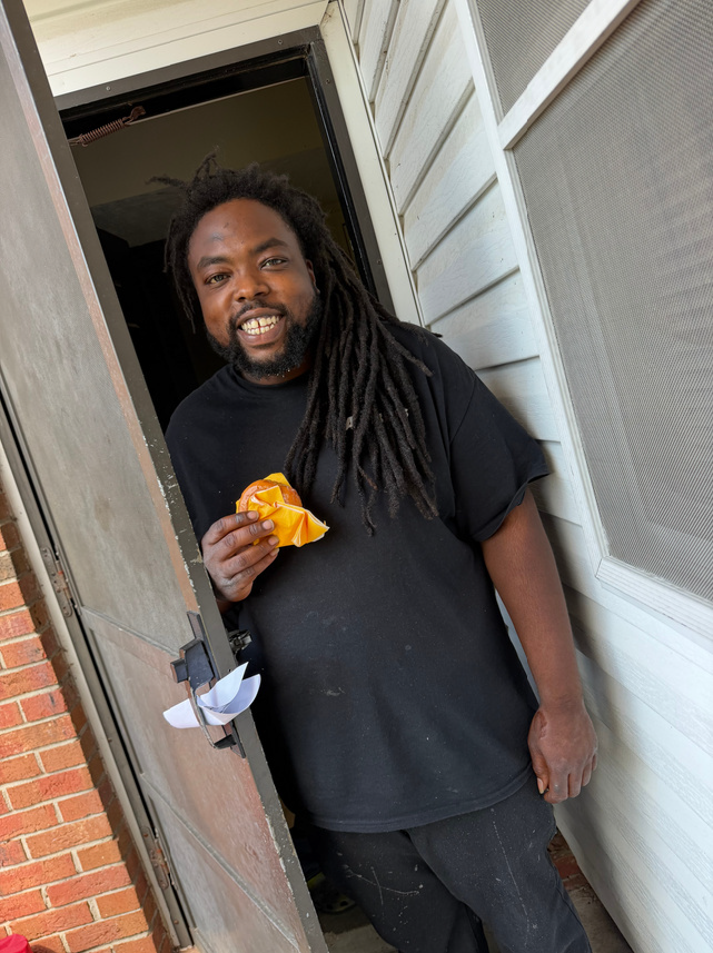 A man smiling and holding a donut.