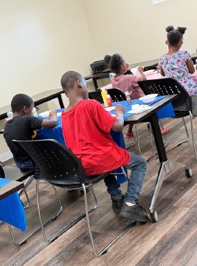 Kids sitting at tables working on art projects.