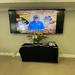 A tv screen showing an image of Mr Lacy Lambert and reading: Lacy's Retirement Celebration, 27 years of service. There are flowers and other items on a table beneath the screen. 