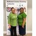 Two women standing in front of a sign for Robeson County Housing Authority.