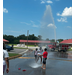 Children on a street playing in water from a fire truck.