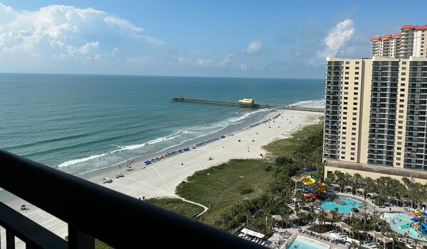 View of the ocean, beach, and hotel from a balcony.