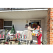 Two women holding presents on a decorated porch. 