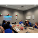  Eight people sitting at  a table focusing on a presentation about Building Championship Roster using MTW Flexibilities. 