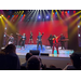  A band with seven members stands and performs on stage. 